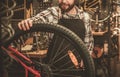 Stylish bicycle mechanic doing his professional work in workshop. Royalty Free Stock Photo