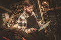 Stylish bicycle mechanic making notes in clipboard in his workshop.