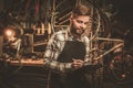 Stylish bicycle mechanic making notes in clipboard in his workshop.