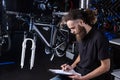 Stylish bicycle mechanic making notes in clipboard in workshop. theme small business selling, repair and service bicycles.