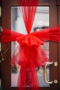 Stylish big christmas red bow on doors, festive decoration of building entrance. Modern christmas decor in city street. Winter Royalty Free Stock Photo