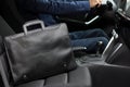 Stylish black business man`s leather bag on the passanger seat near driver in the car with modern interior