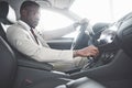 Stylish black businessman sitting behind the wheel of new luxury car. Rich african american man