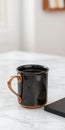 Stylish black ceramic mug with copper handle on a textured surface Royalty Free Stock Photo
