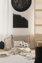 Stylish black chandelier and black and white abstract painting in japanese inspired beige bedroom