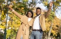 Stylish black couple posing with raised hands in autumn park Royalty Free Stock Photo