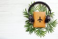 Stylish black headphones on passport with plane and green palm l Royalty Free Stock Photo