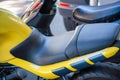 Stylish black leather bike seat with visible yellow motorcycle or bike with black tires and background motors parked in the city Royalty Free Stock Photo