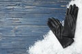 Stylish black leather gloves and artificial snow on blue wooden table, top view. Space for text Royalty Free Stock Photo