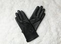 Stylish black leather gloves on artificial snow, top view Royalty Free Stock Photo