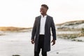 Stylish black man in classic white shirt, trousers and coat, posing outdoors at sunset, successful man Royalty Free Stock Photo