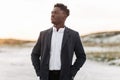 Stylish black man in classic white shirt, trousers and coat, posing outdoors at sunset, successful man Royalty Free Stock Photo