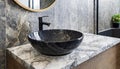 Stylish black marble round vessel sink and wall mounted faucet on stone wall. Interior design of modern bathroom Royalty Free Stock Photo