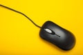 Stylish black optical computer mouse isolated on a yellow background. View from above Royalty Free Stock Photo