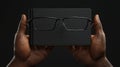 Stylish Black Rectangular Glasses Resting on a Luxurious Black Notebook Held by Dark Hands AI generated. Royalty Free Stock Photo