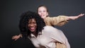 Stylish black stepmother holds adopted schoolgirl on backs