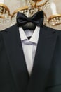 Stylish black suit with white shirt and bow tie on hanger on lux Royalty Free Stock Photo