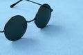 Stylish black sunglasses with round glasses lies on a blanket made of soft and fluffy light blue fleece fabric. Fashionable backgr Royalty Free Stock Photo