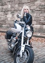 Stylish blond woman posing with motorcycle. Royalty Free Stock Photo