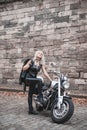 Stylish blond woman posing with motorcycle.