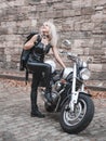 Stylish blond woman posing with motorcycle. Royalty Free Stock Photo