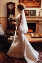 Stylish blonde bride walking with bouquet to groom in the morning in hotel. wedding day concept. beautiful woman back in white Royalty Free Stock Photo