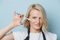 Stylish blonde female hairdresser holding open scissors next to her face Royalty Free Stock Photo