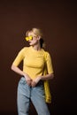 stylish blonde girl with string bag wearing yellow sunglasses and looking away