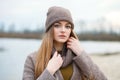 Stylish blonde woman in trendy urban outwear posing cold weather on the river bank. Vintage filter film saturated color. Fall mood Royalty Free Stock Photo