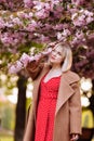 Stylish blonde in a red dress in the spring city. Beautiful girl in red dress posing on city streets. Stunning young woman walking Royalty Free Stock Photo