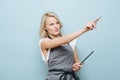 Stylish blonde woman hairdresser aiming with sissors to a side over blue Royalty Free Stock Photo