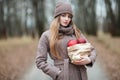 Stylish blonde woman in trendy urban outwear posing cold weather forest park alley with package of red apples. Fall mood concept. Royalty Free Stock Photo