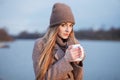 Stylish blonde woman in trendy urban outwear posing cold weather on the river bank. Vintage filter film saturated color. Fall mood Royalty Free Stock Photo