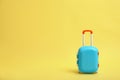 Stylish blue little suitcase on yellow background