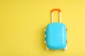 Stylish blue little suitcase on yellow background. Space for text