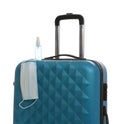Stylish blue suitcase, antiseptic spray and protective mask on white background. Travelling during coronavirus pandemic