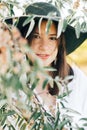 Stylish boho girl with modern earrings posing among green olive branches in soft evening light. Happy young fashionable woman Royalty Free Stock Photo