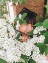 Stylish boho girl taking selfie with white flowers on green branches of bird-cherry tree. Girl portrait with beautiful bird cherry Royalty Free Stock Photo