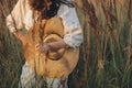 Stylish boho woman posing with straw hat in hand close up among wild grasses in sunset. Atmospheric moment. Summer travel. Young Royalty Free Stock Photo