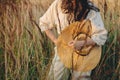 Stylish boho woman posing with straw hat in hand close up among wild grasses in sunset. Atmospheric moment. Summer travel. Young Royalty Free Stock Photo