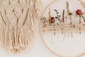 Stylish boho wreath with dry flowers and macrame hanging on white wall. Modern floral arrangement and creative handmade decor in