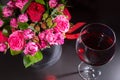 Stylish bouquet of pink and red roses and red ribbon in a circular black box near a glass with wine Royalty Free Stock Photo