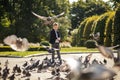 Stylish boy  in the park feeds pigeons. There are a lot of birds. Baby happy feed hungry pigeons Royalty Free Stock Photo