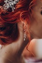 Stylish bride detail, luxury earring jewelry and red hair curl, beautiful wedding dress. rustic wedding morning preparation.