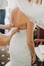 Stylish bride getting dressed in modern gown with bridesmaids and mom in hotel room. Morning preparation before wedding ceremony. Royalty Free Stock Photo