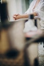 Stylish bride getting her makeup by professional makeup artist in morning light in hotel room. Morning preparations. Bride sitting