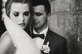 Stylish bride and groom gently embracing in european city street, face closeup. Gorgeous wedding couple of newlyweds sensually