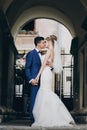 Stylish bride and groom gently kissing in sunny european city street. Gorgeous wedding couple of newlyweds embracing in old Royalty Free Stock Photo