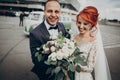 Stylish bride and groom hugging and laughing,having fun near retro car with boho bouquet. luxury wedding couple newlyweds, happy Royalty Free Stock Photo