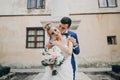 Stylish bride and groom kissing sensually in sunny european city street. Gorgeous wedding couple of newlyweds embracing at old Royalty Free Stock Photo